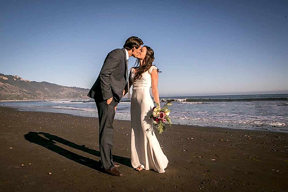 Two people kiss, at the beach.