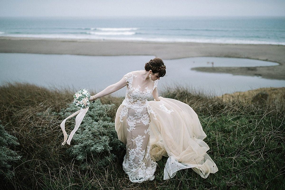 A woman walks through tall grass at the seashore