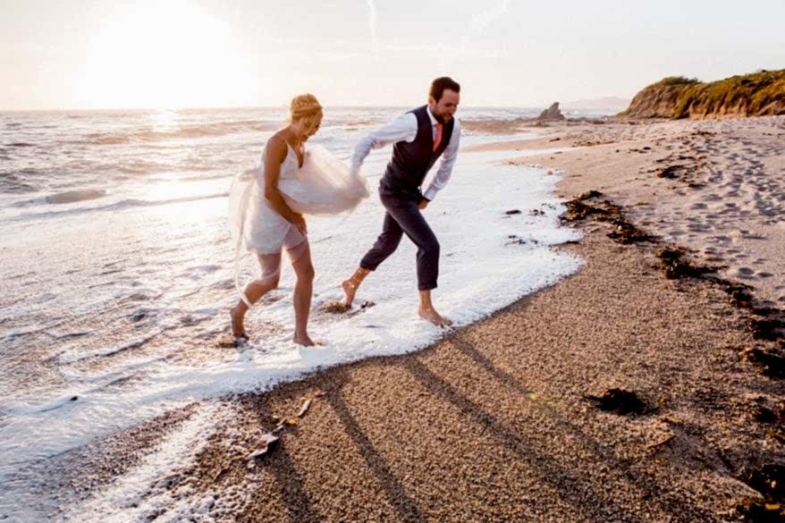 A man and woman run from the water at a beach
