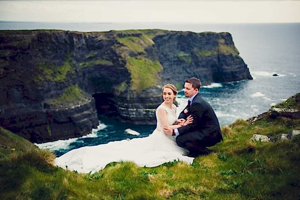 A couple sit together on a high cliff