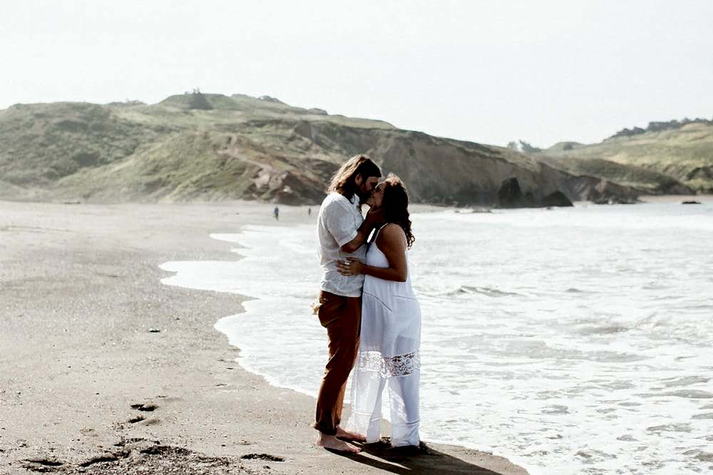A couple kiss during a casual beach wedding