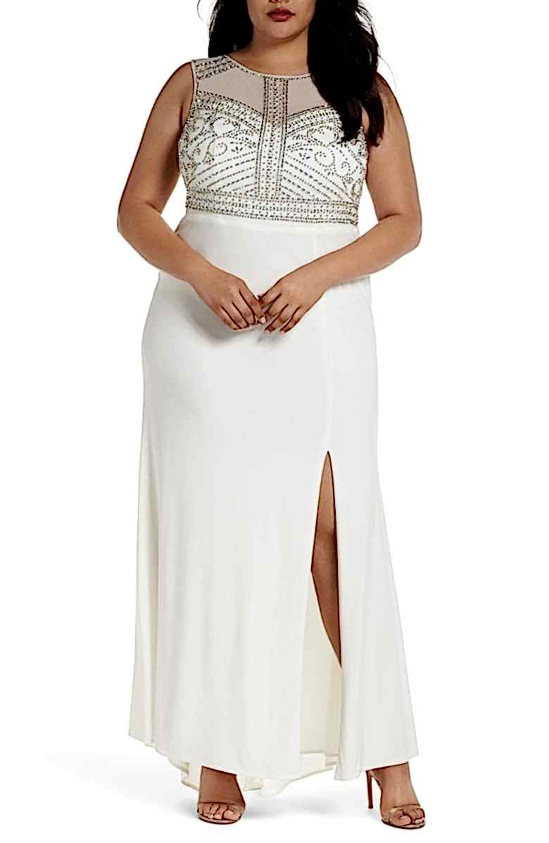 A woman wears a white column dress with high slit and beaded empire bodice