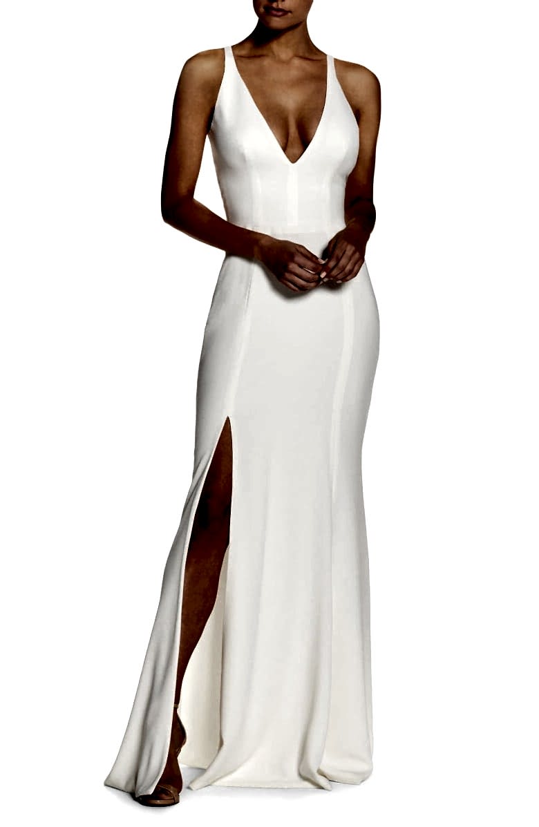 A woman wears a deep v-neck sleeveless white dress with high front side slit