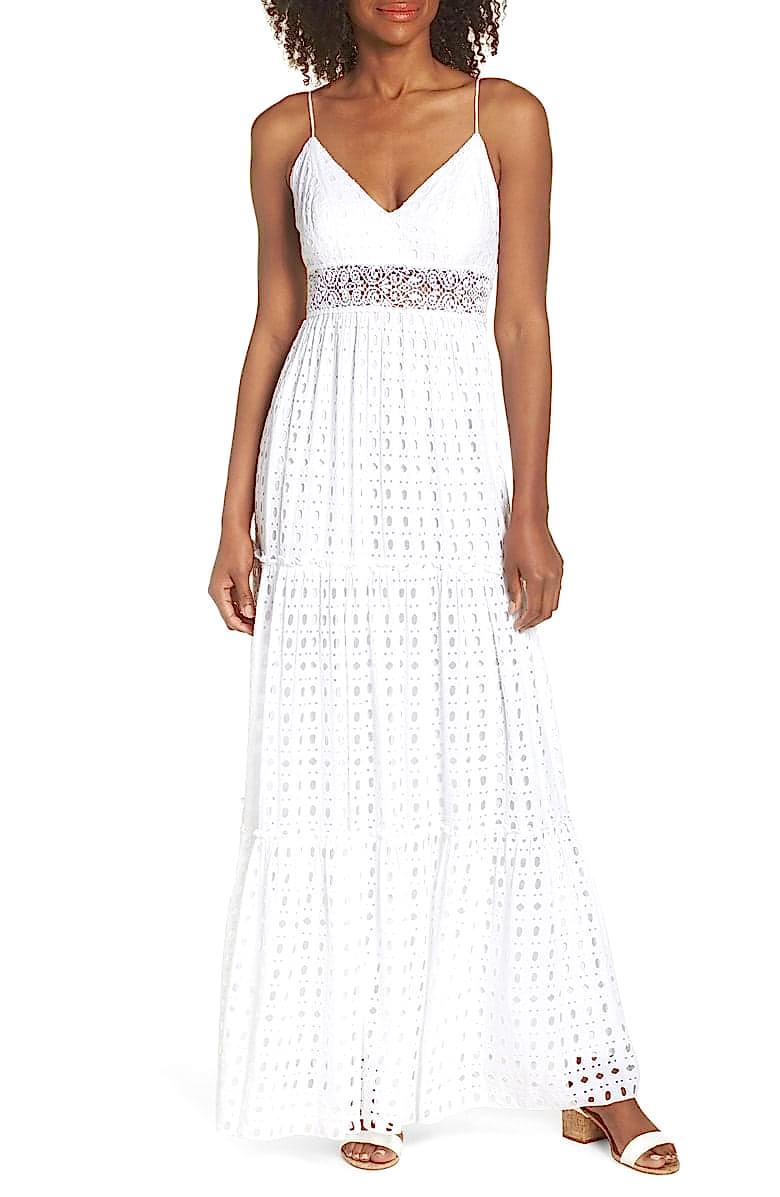 A woman wears a white eyelet dress with spaghetti straps