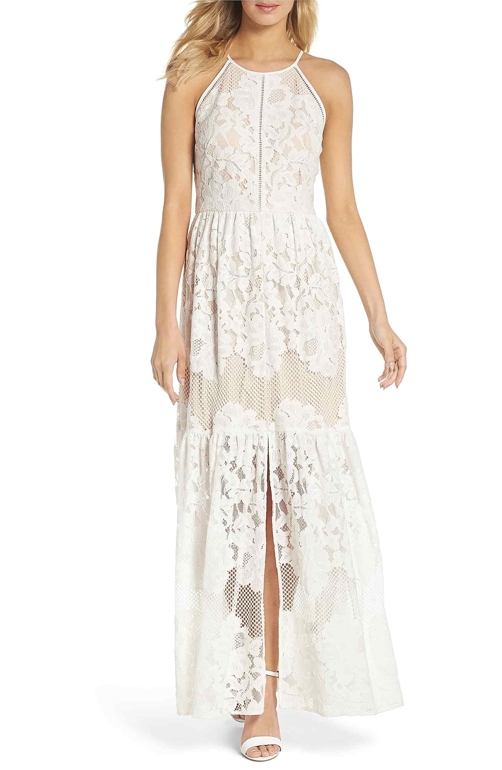 A woman wears a white lace dress with high halter-style neckline and lightly gathered two-tiered ruffle skirt
