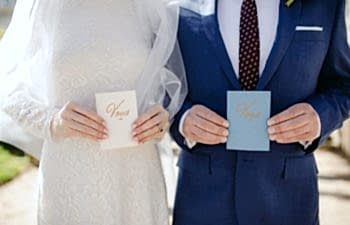 Wedding Vows held by a bride in a white dress and veil and groom in a blue suit