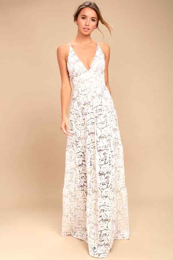 A woman wears a white sheer lace dress with a nude underdress, with a deep v-neck and short spaghetti straps