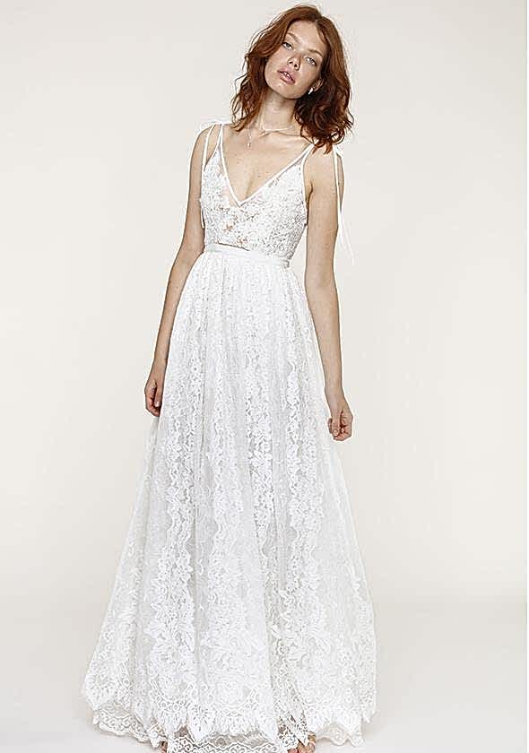 a woman wearing a white lace dress with a fitted bodice, plunging neckline, and shoulder tie spaghetti straps