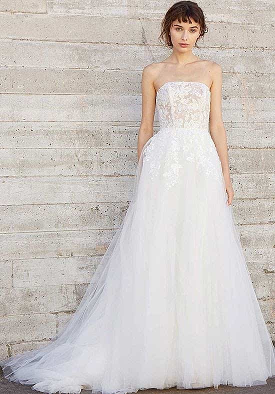 A woman wears a strapless white dress with a lace bodice and tulle skirt