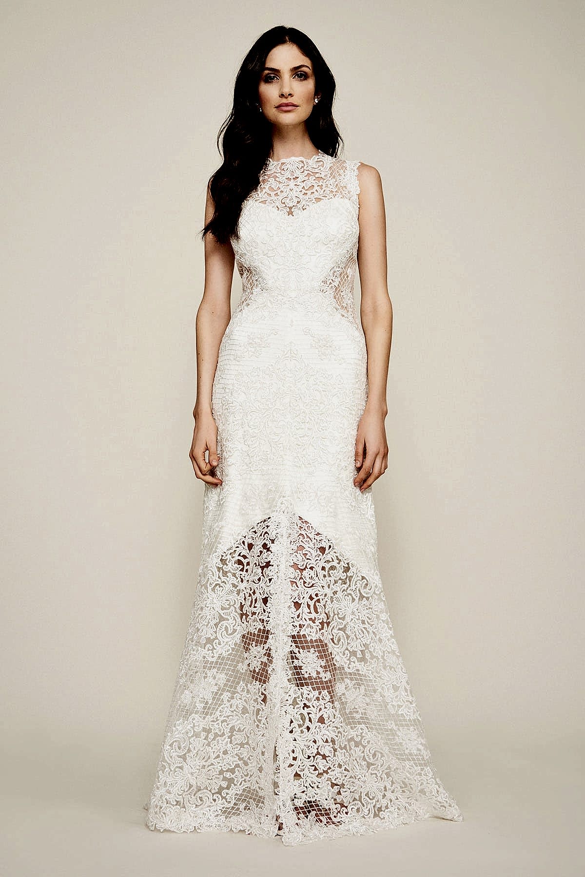 A woman wears a white lace dress with a sweetheart neckline on the underdress, body-con side waist cutouts, and a high-low under skirt (with neck high and floor-length sleeveless lace overlay)