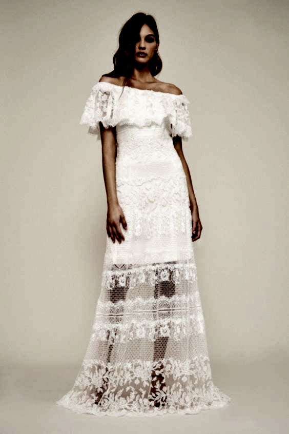 A woman wears a white lace dress with off-the-shoulder ruffle bodice