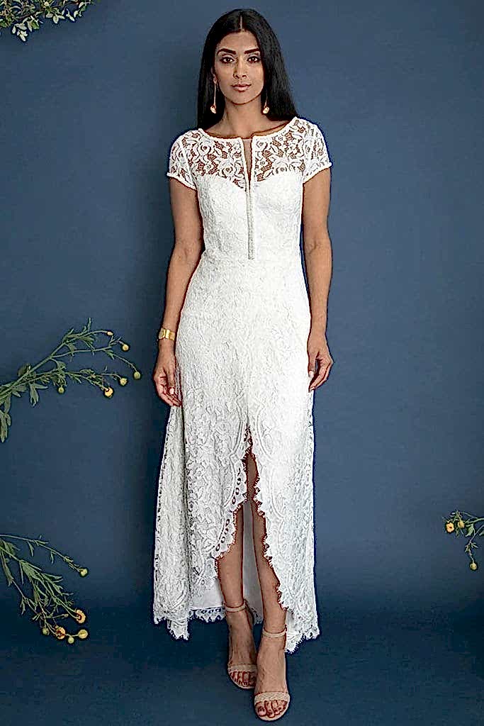 A woman wears an ankle-length white lace dress with short sleeves and a high center slit