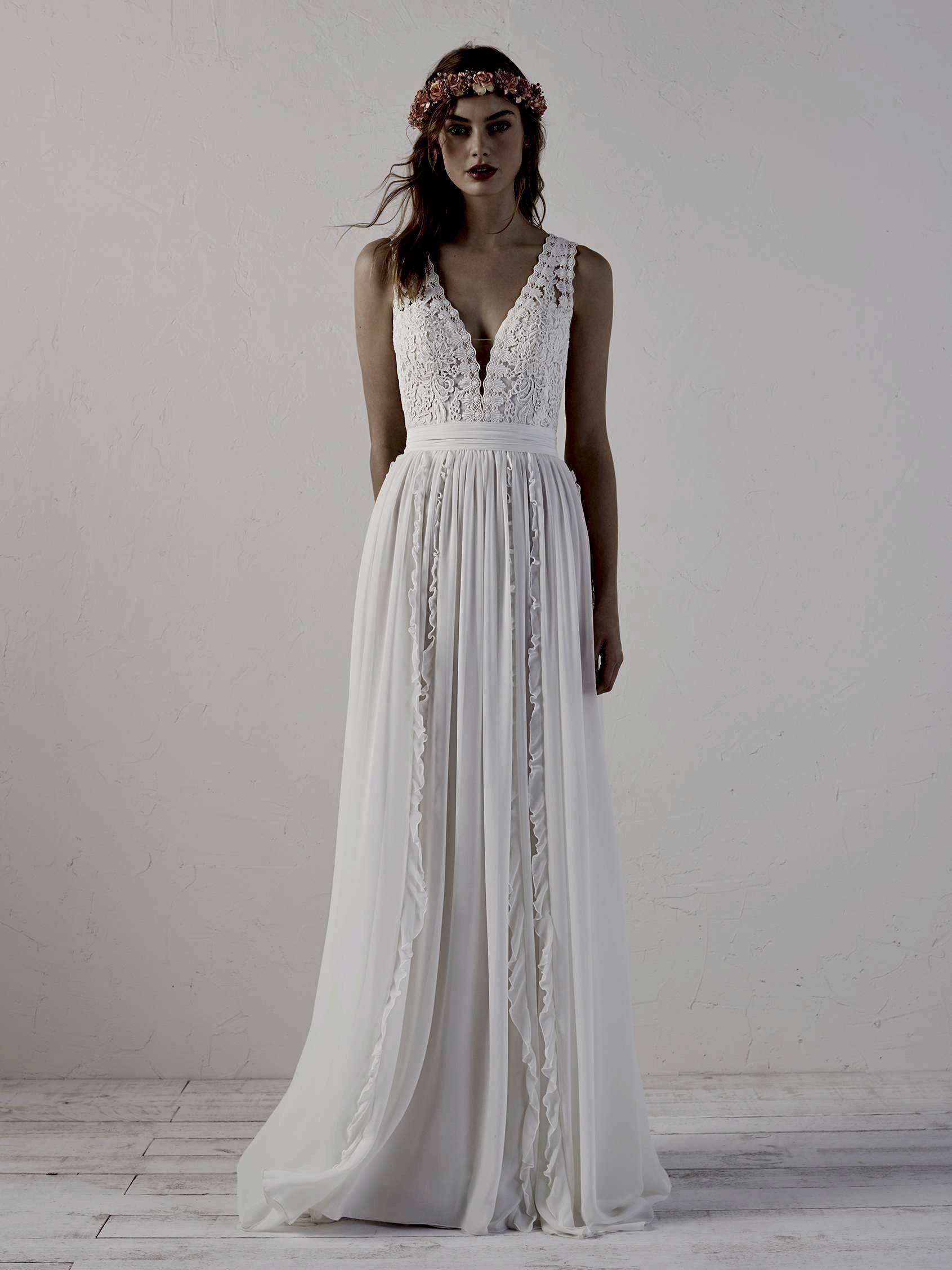 A woman wears a white dress with a sleeveless lace bodice with a plunge v-neck and a ruffle accented skirt