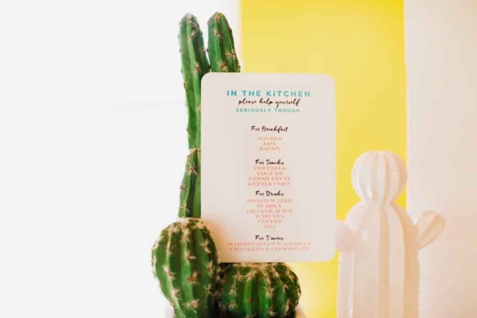 a full color printed card with rounded edges that reads "In the Kitchen" and details food available for snacking. the sheet sits on a small cactus in front of a yellow wall