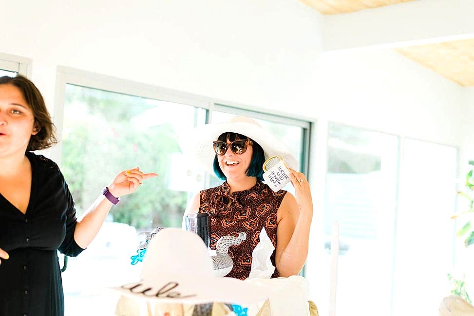 A woman in a white sunhat unpackages her personalized tote bag goodies and holds a mug with gold trim and smiles
