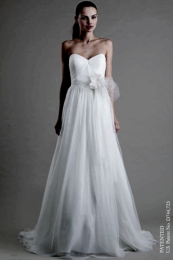 A woman wears a strapless white dress with a straight but full tulle skirt and tulle bow on the front side waist