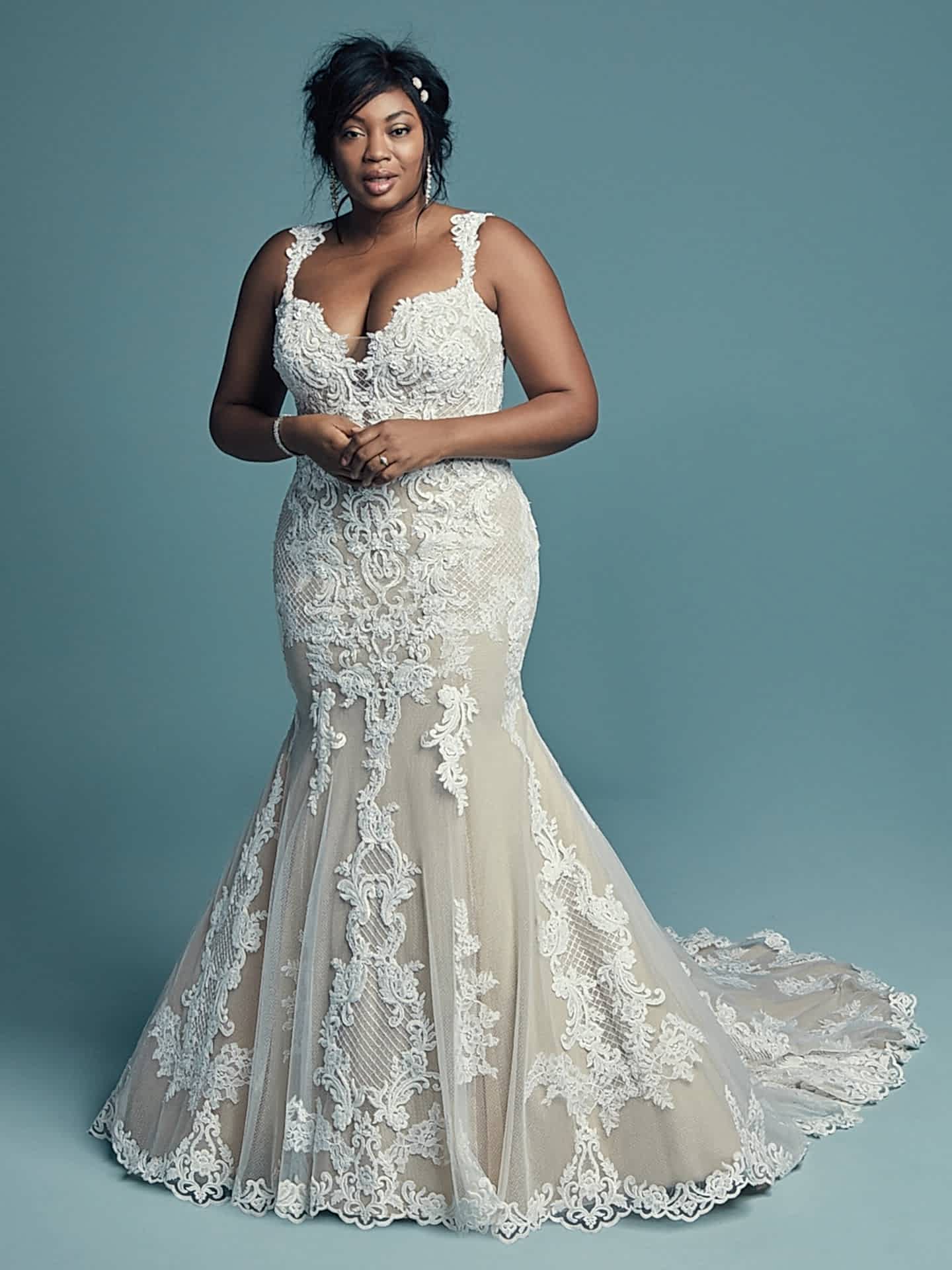 A woman wears an off-white dress with white lace overlay, lace straps, and a mermaid skirt
