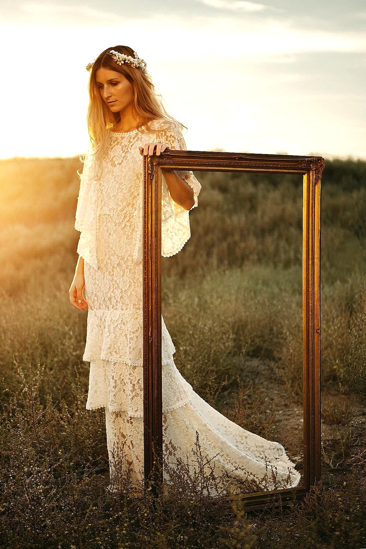 A woman wears a white lace dress with a high neckline, billowing sleeves and a tiered skirt