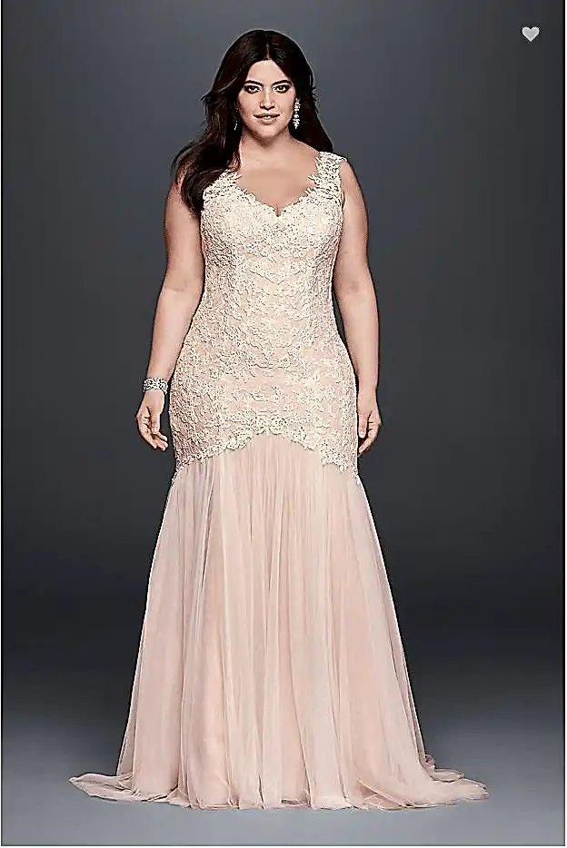 A woman wears a blush trumpet-style sleeveless dress with v-neck and lace bodice extending below hips with tulle skirt below