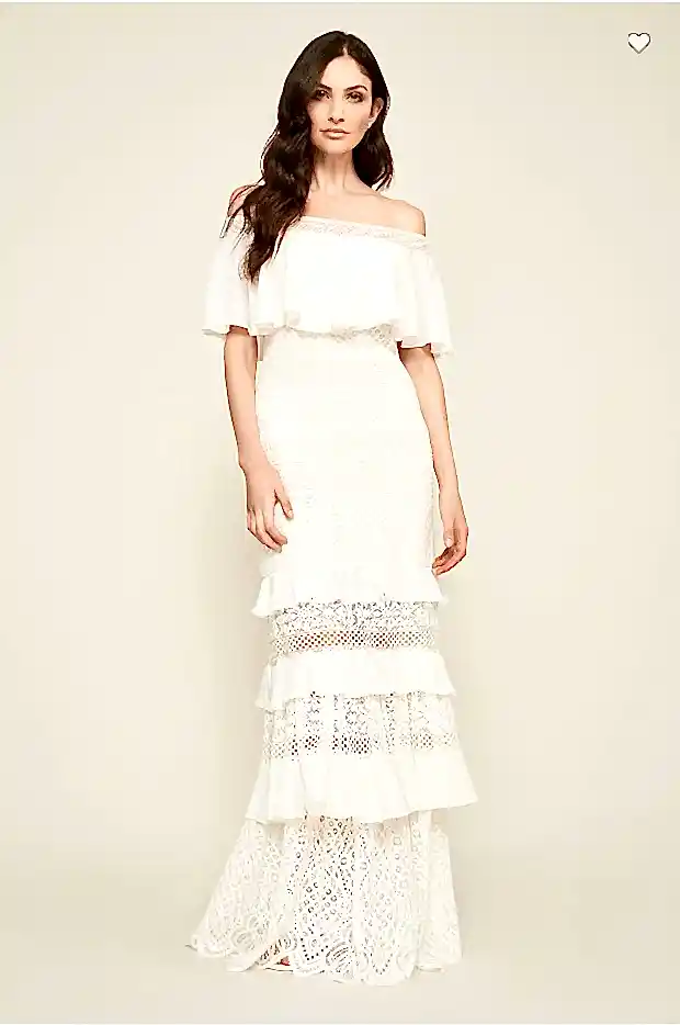 A woman wears a white ruffle-bodice crocheted lace dress with peek-a-boo tiered skirt