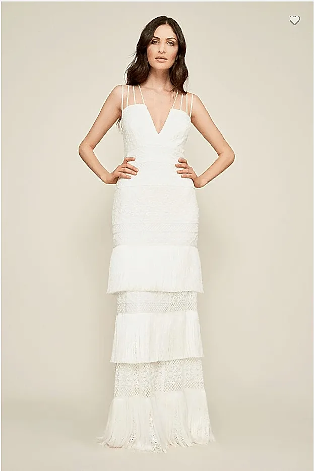 a woman wears a white column dress with lace and fringe accents and four spaghetti straps