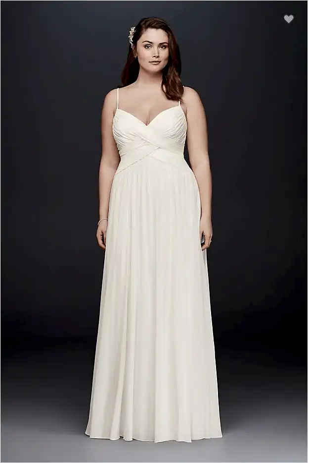 A woman wearing a white dress with a cross front ruched bodice and spaghetti straps with a flowing a-line skirt