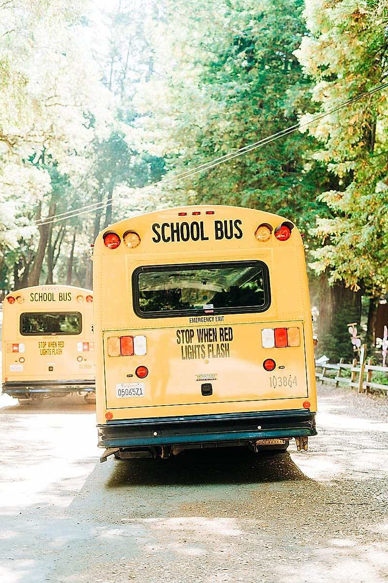 School buses driving away, past the trees at the compact summer camp in la Honda, CA