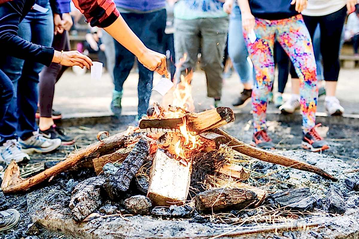 hands burning small pieces of paper in the bonfire at the compact summer camp in la Honda, CA