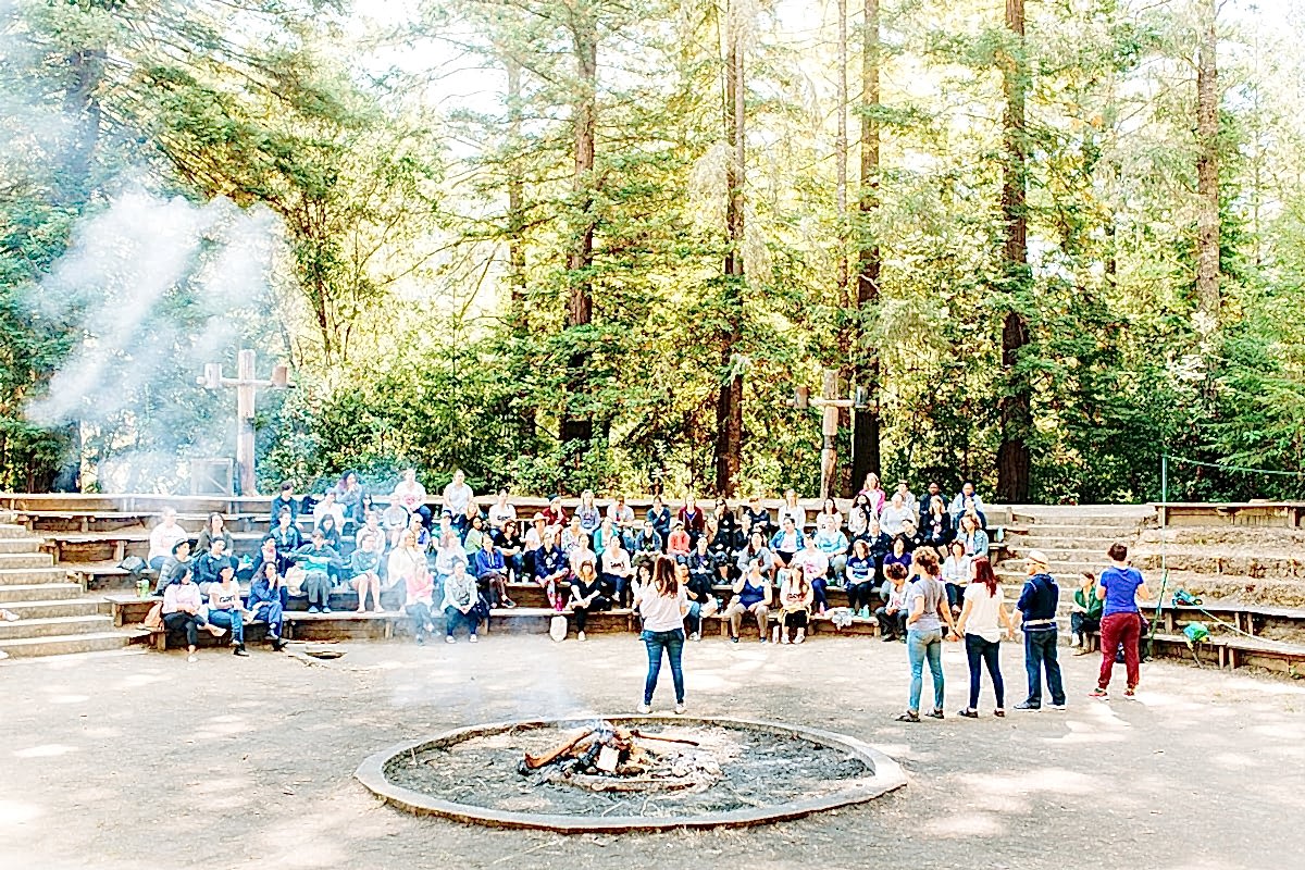 Farewell ceremony and bonfire, with the whole camp sitting on benches in an amphitheater among the trees at the compact summer camp in la Honda, CA