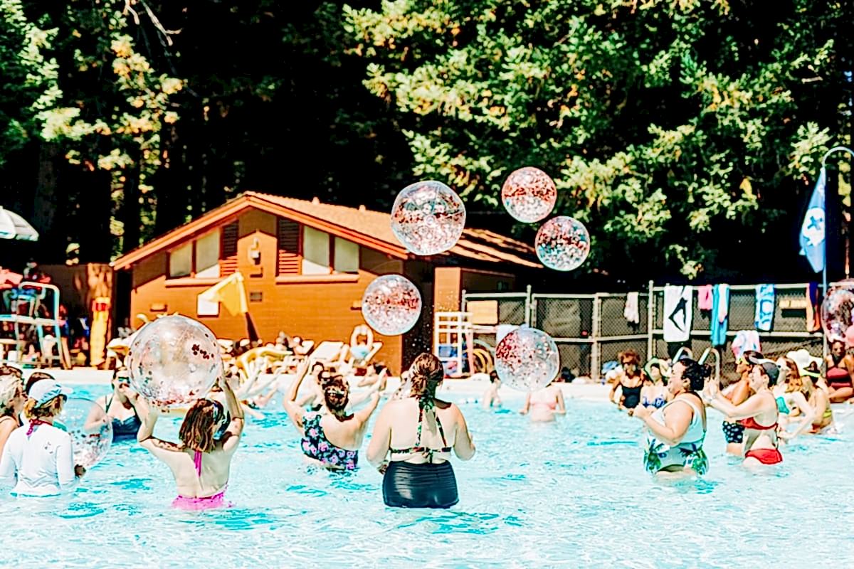 Women in a pool with lots of glittery beach balls being tossed in the air at the compact summer camp in la Honda, CA