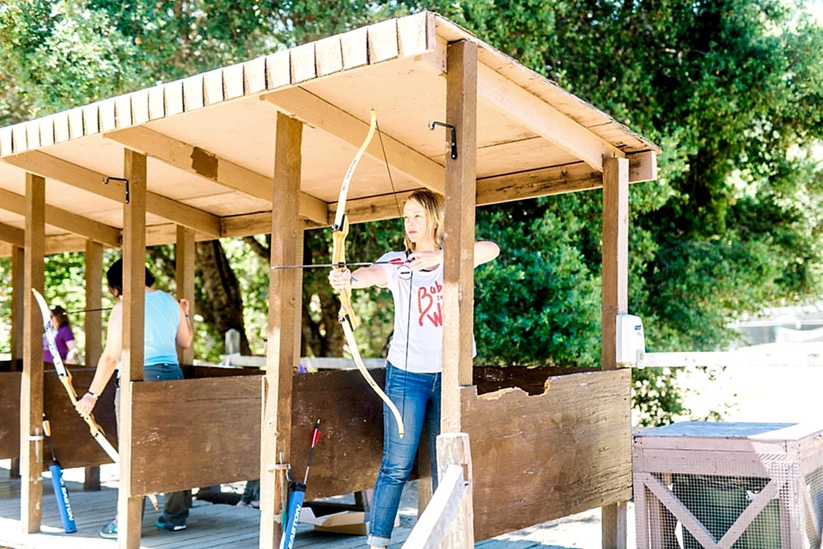 A woman preparing her arrow for archery at the compact summer camp in la Honda, CA