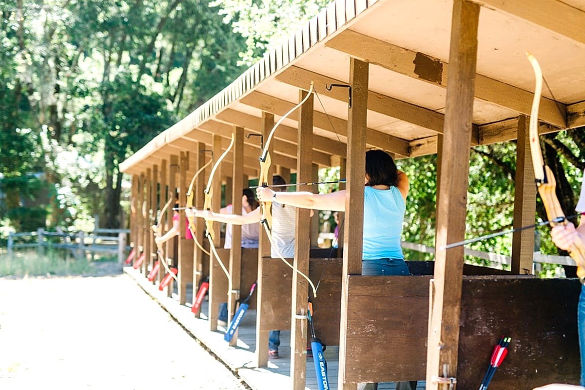 women lined up with bows and arrows for archery at the compact summer camp in la Honda, CA