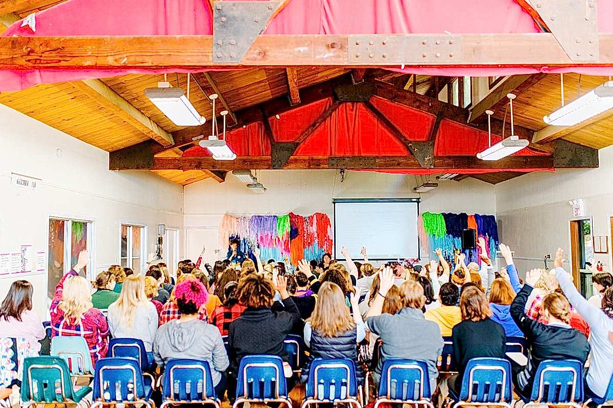 A large group of women, many raising their hands, during the keynote by Cyndie Spiegel at the compact summer camp in la Honda, CA