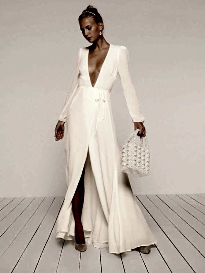 Blonde woman in empty room wearing white gown and holding bag