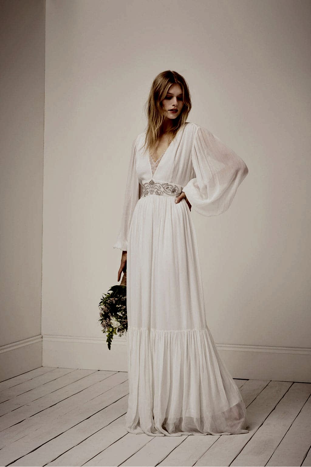 Blond woman holding flowers and a white winter wedding dresses