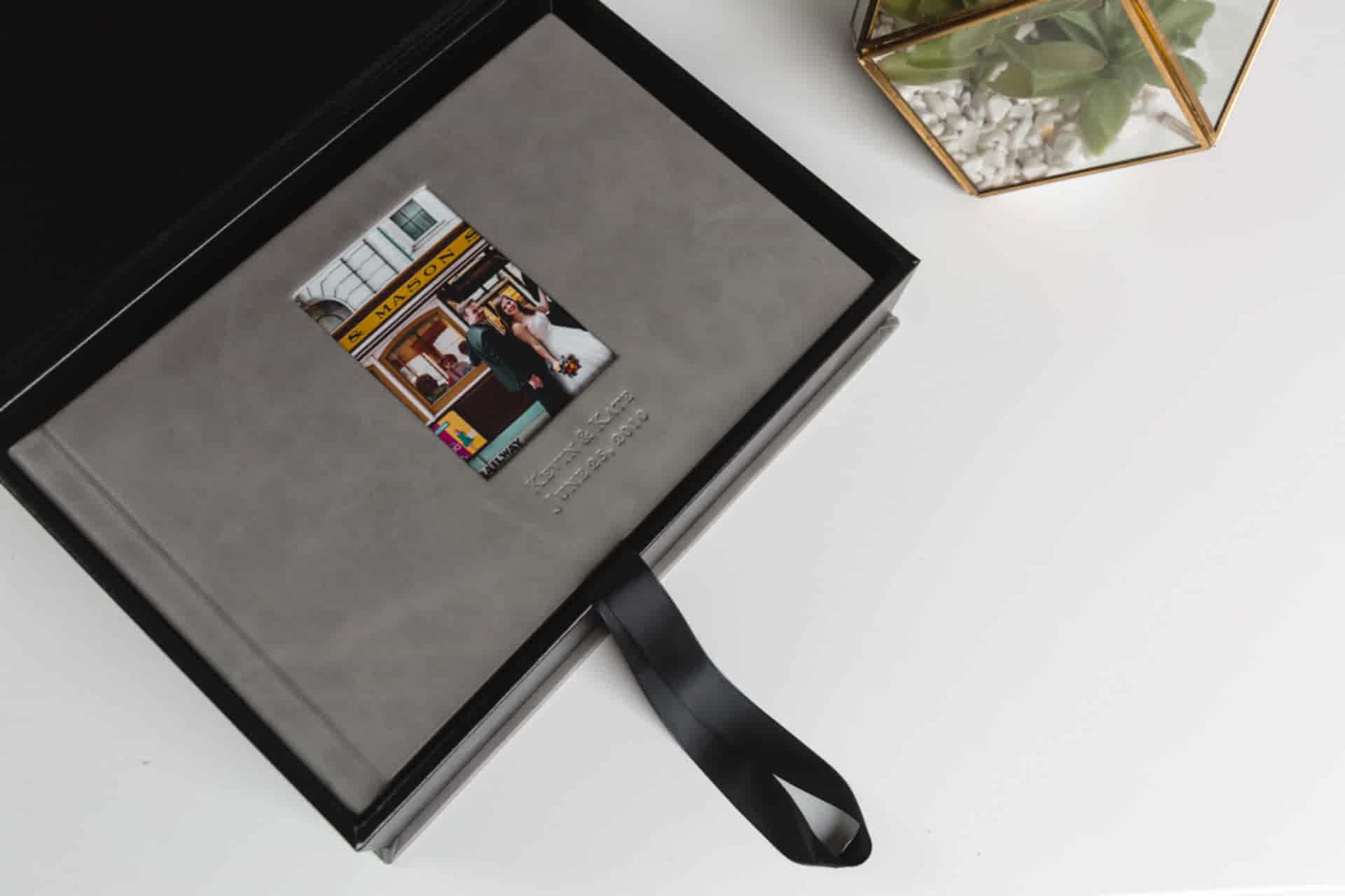 A grey leather-bound photo album sits in a matching box from Albums Remembered