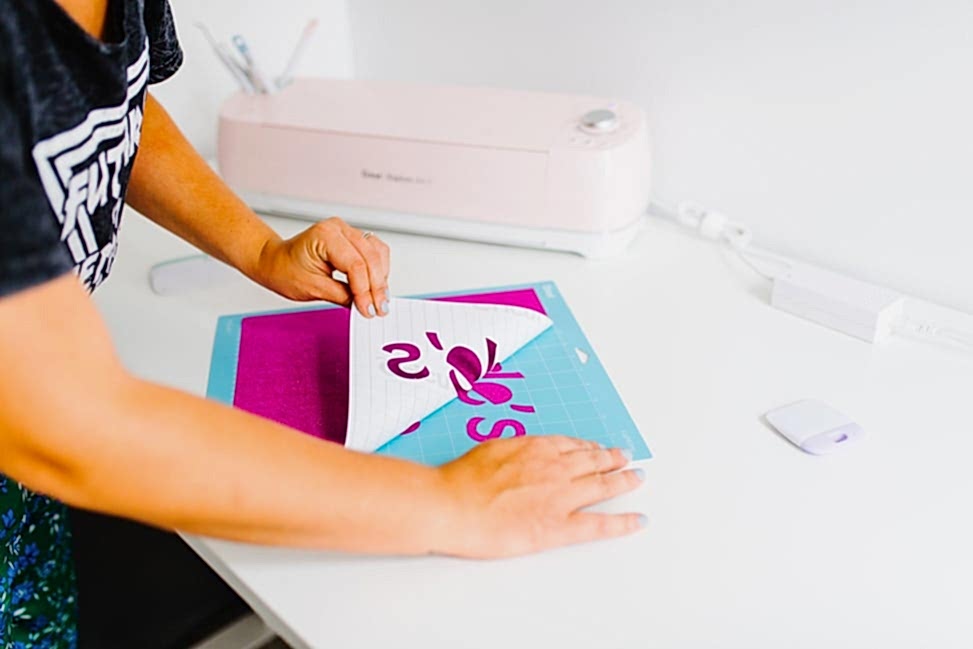 A woman peeling away the background page for the Cricut Explore Air 2 Machine from Michael's Weddings