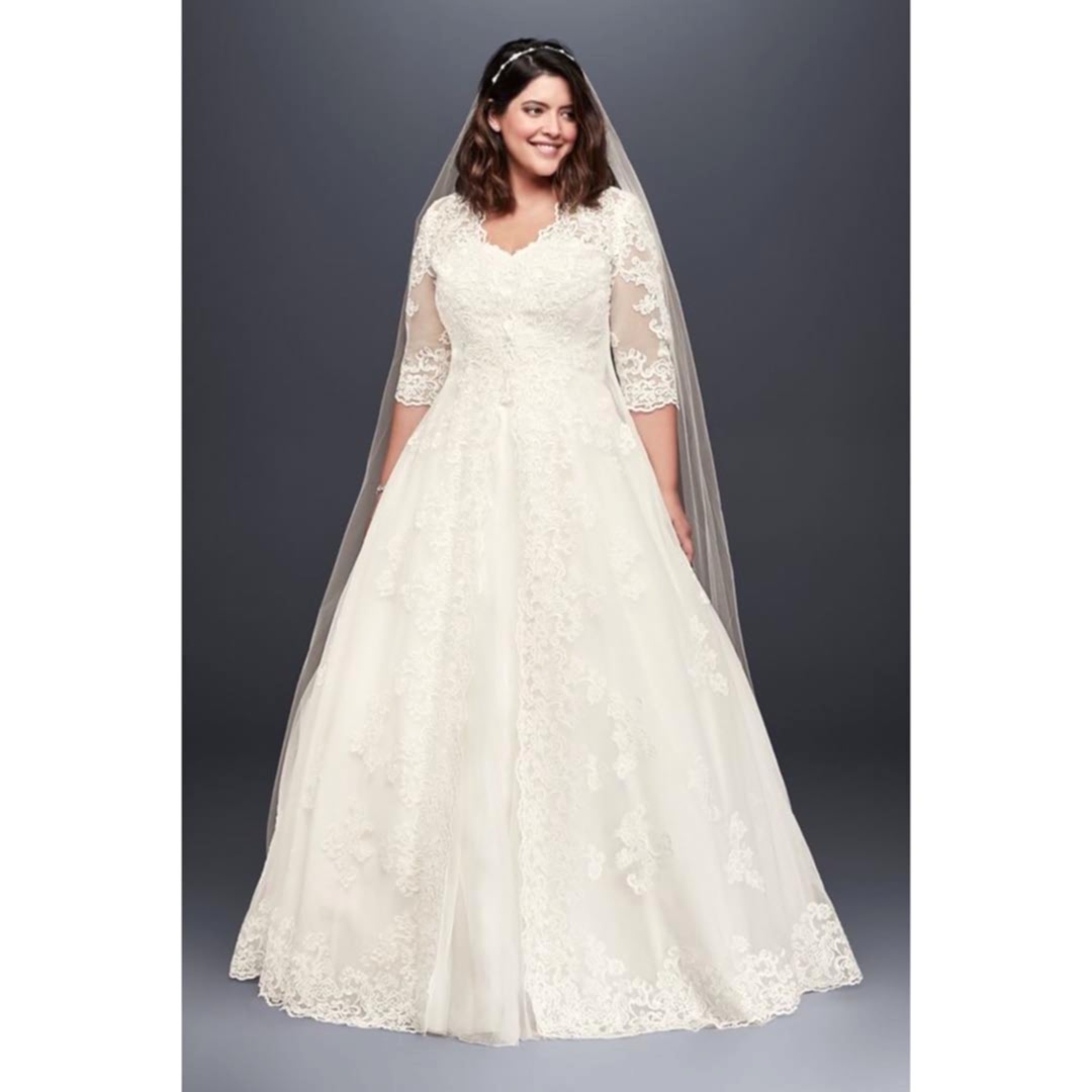 Brunette woman in grey room wearing veil, ballgown and lace jacket