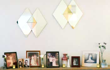 A table with a variety of frames with vintage images of married couples sits below two geometric diamond mirrors