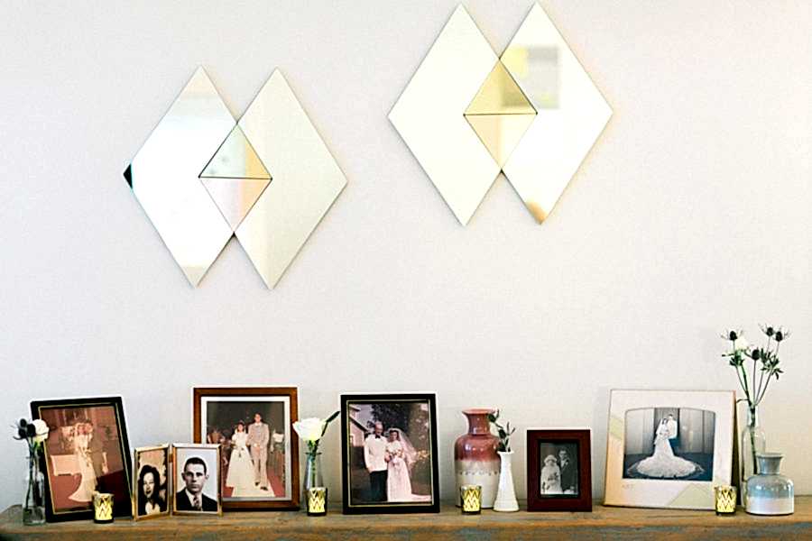A table with a variety of frames with vintage images of married couples sits below two geometric diamond mirrors