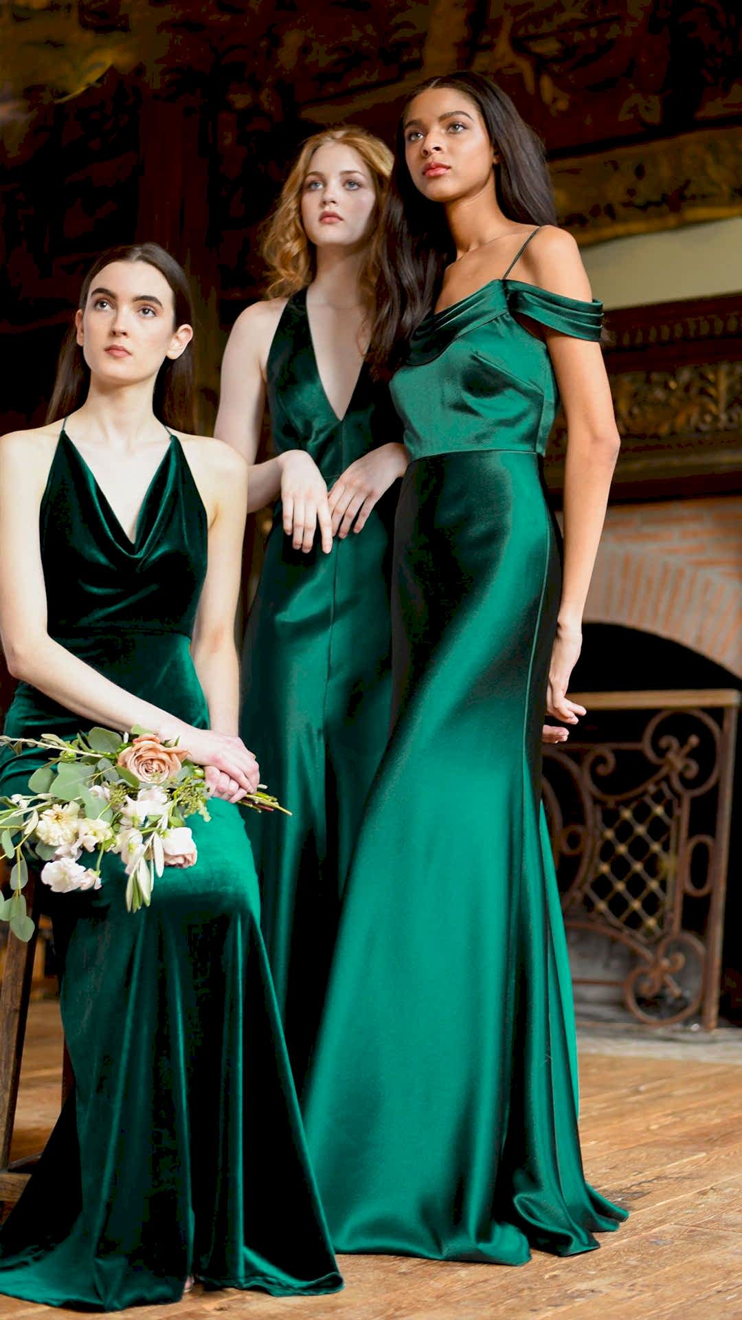 Three women wearing dresses in winter wedding colors: dark green dresses, holding flowers