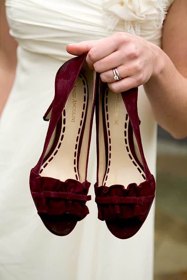 Woman holding pair of winter wedding colors burgundy/oxblood velvet heels