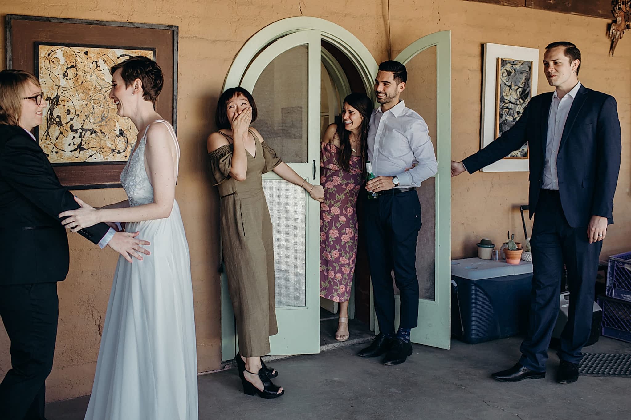 The reaction of several guests to a queer wedding couple experiencing their first look is documented in a photo by Betty Clicker