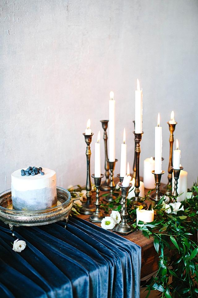 Cake and candles on sideboard with a winter wedding colors indigo velvet tablecloth