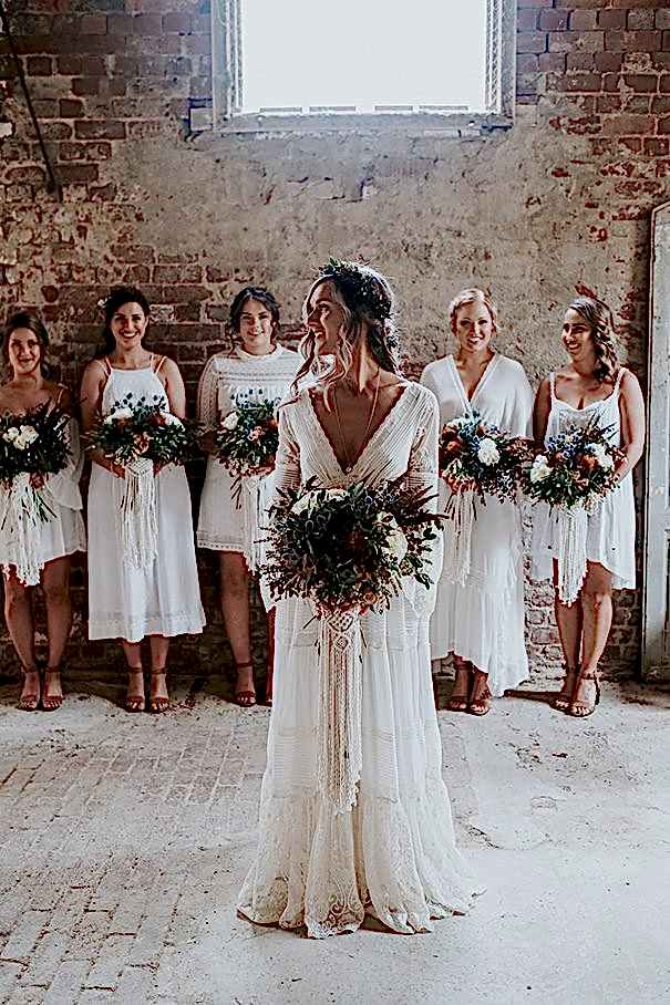 Group of women in a room, all wearing white winter wedding colors and holding bouquets