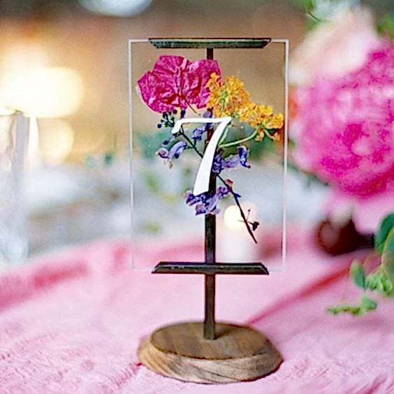 wedding ideas for table numbers—pressed flowers in a glass frame with a wood pedestal stand with the table number on the front