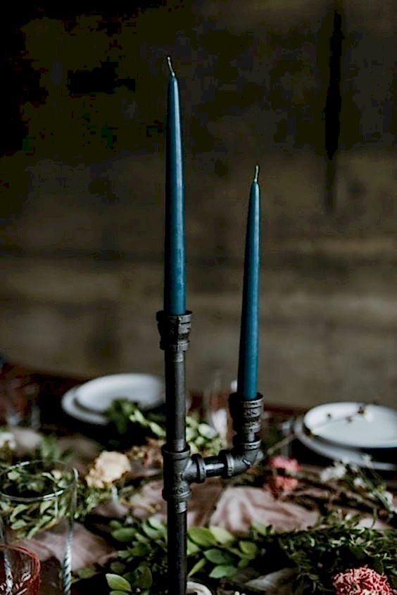 wedding ideas for centerpieces—dark teal colored candles stick in a black industrial pipe candelabra