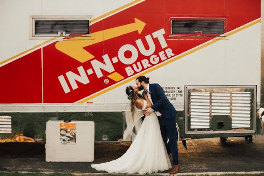 weddings ideas of a couple in a wedding dress and suit kissing in front of in and out truck
