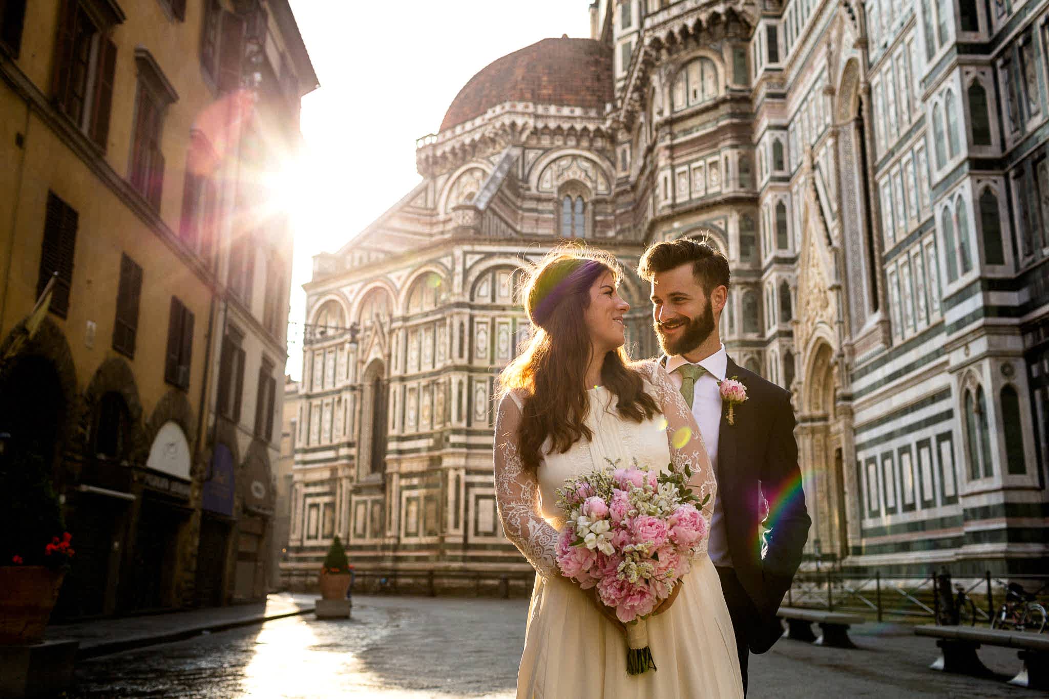 A couple in wedding clothes look at each other smiling at their old-world Europe destination wedding locale