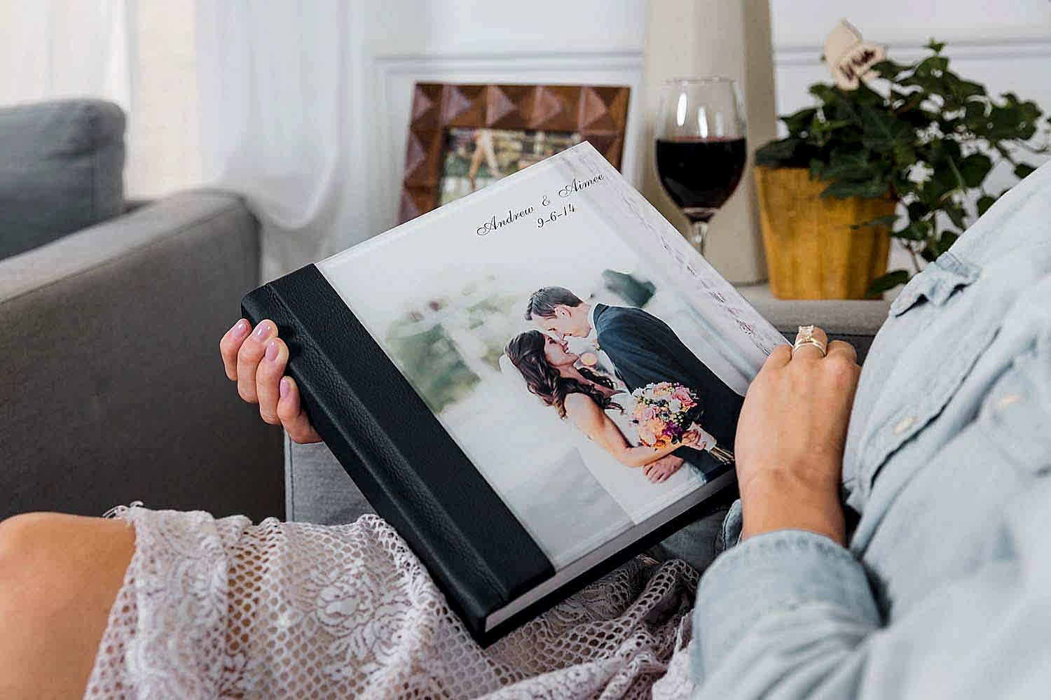 shot of woman holding a flat lay wedding albums by Albums Remembered with a photo cover of a bride and groom